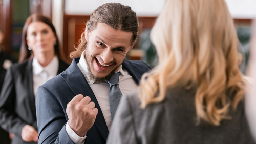 selective focus of excited businessman showing win gesture near advocate and prosecutor in court