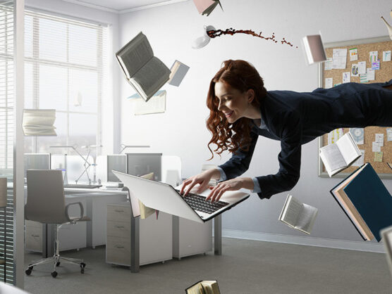 Young businesswoman levitating over workplace. Mixed media