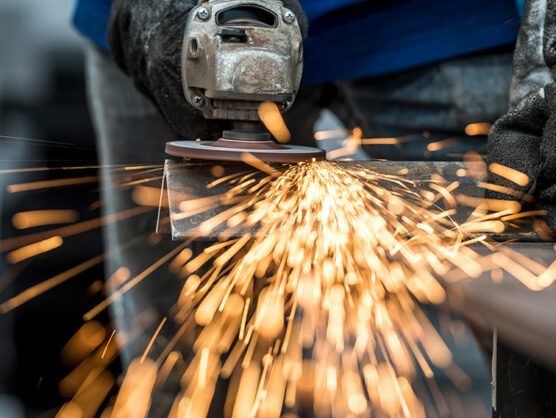 Industrial worker cutting metal with many sharp sparks