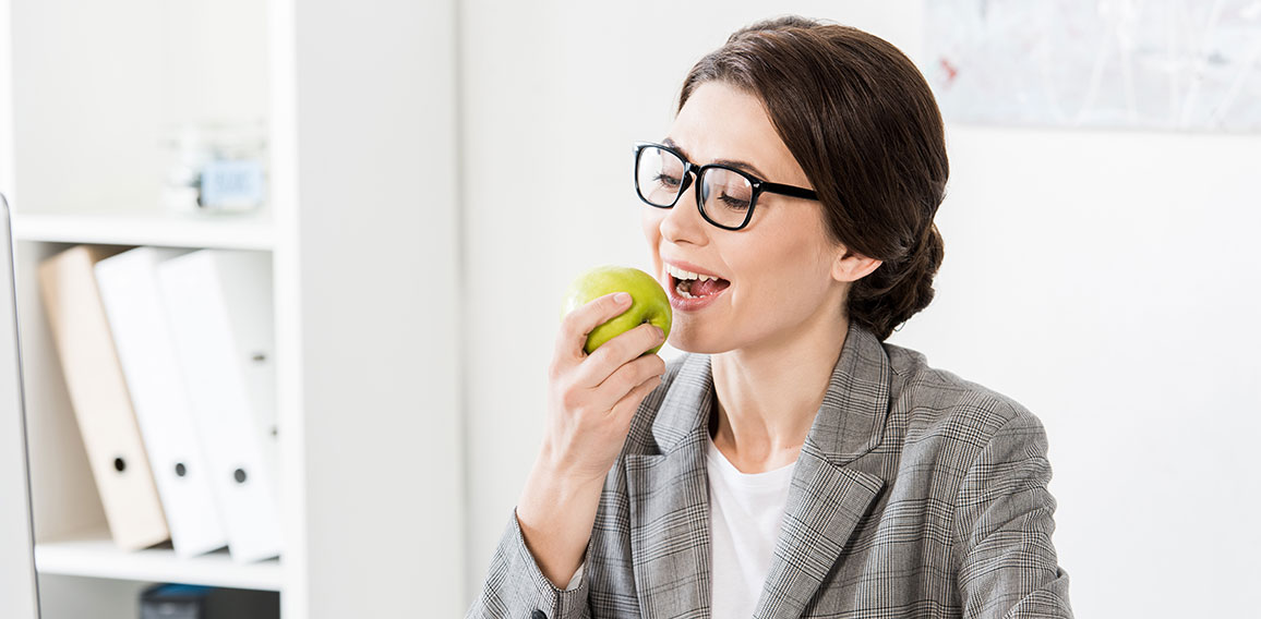 Geschäftsfrau isst Apfel im Büro.