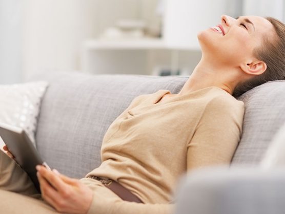 Frau mit Tablet entspannt auf Sofa