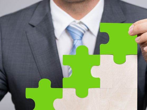 Geschäftsmann hält grünes Puzzleteil