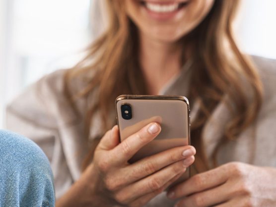 Frau lächelt mit Smartphone in der Hand