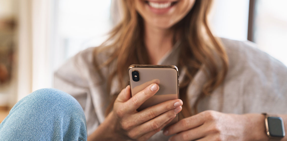 Frau lächelt mit Smartphone in der Hand