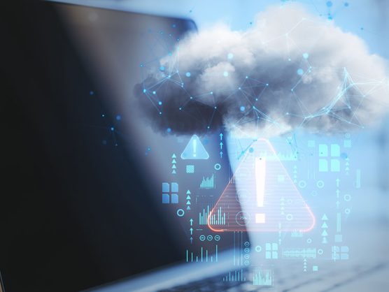 Digitale Wolke mit Warnsignal schwebt vor Laptop