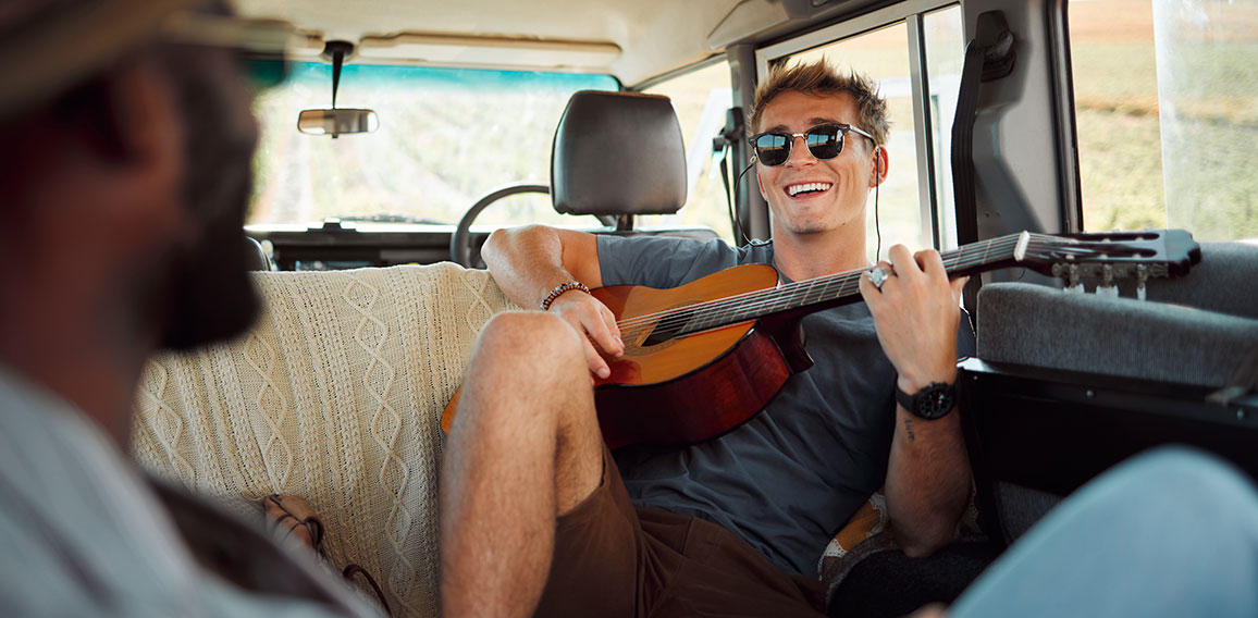 Mann mit Gitarre und Sonnenbrille in Kleinbus
