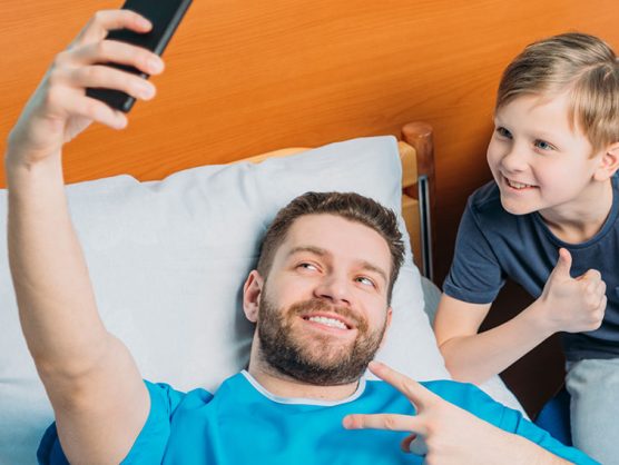 Vater in Krankenbett macht Selfie mit Sohn