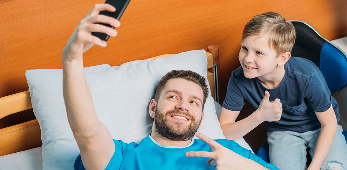 Vater in Krankenbett macht Selfie mit Sohn