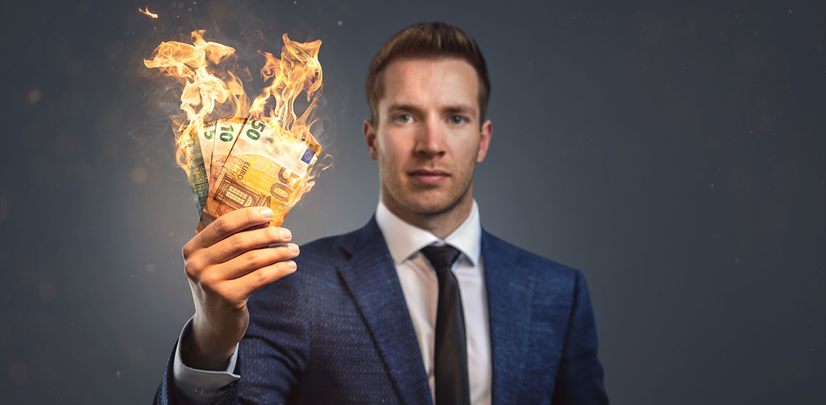 Anzugträger mit brennenden Geldscheinen in der Hand