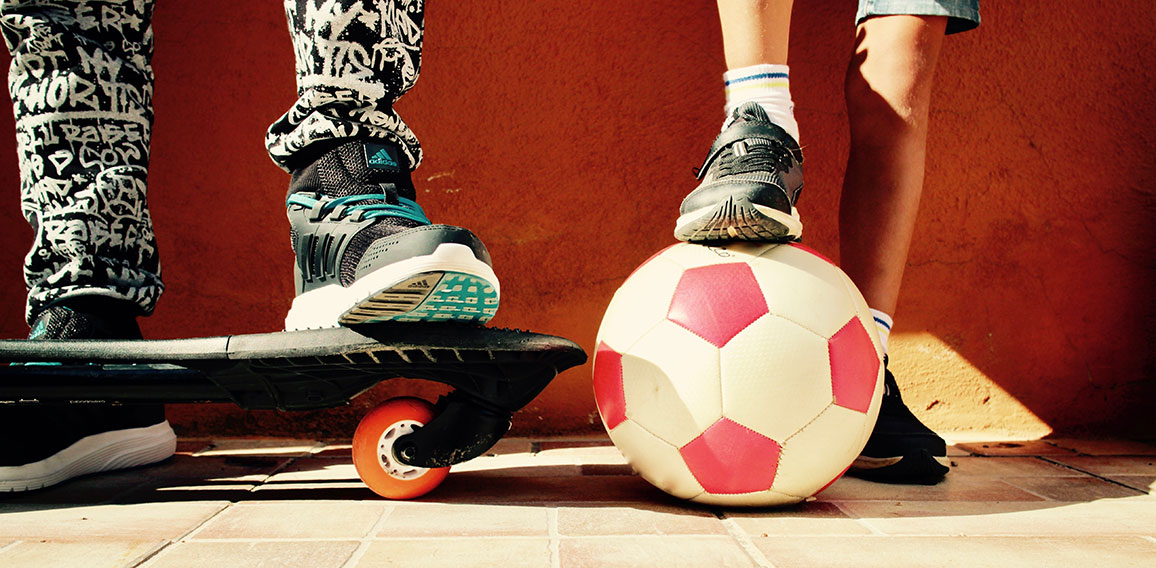 Close-up auf Schuhe von Kindern mit Skateboard und Fußball