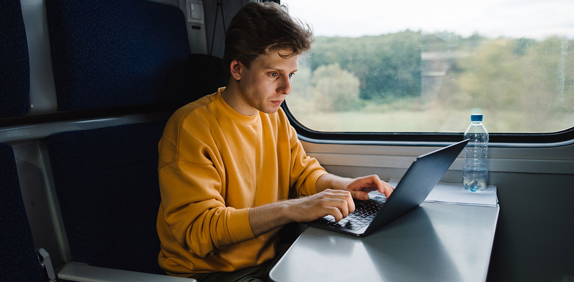 Mann in Zug arbeitet an Laptop