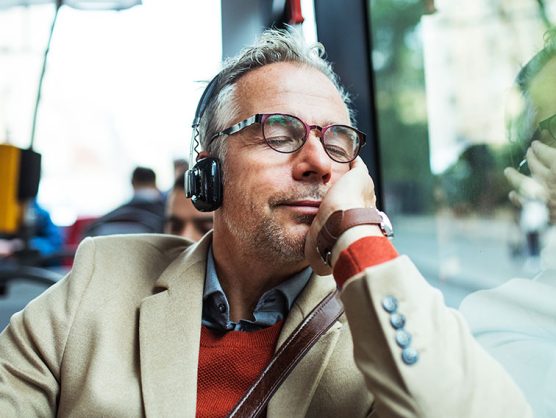 Mann mit Kopfhörer sitzt entspannt in Bus