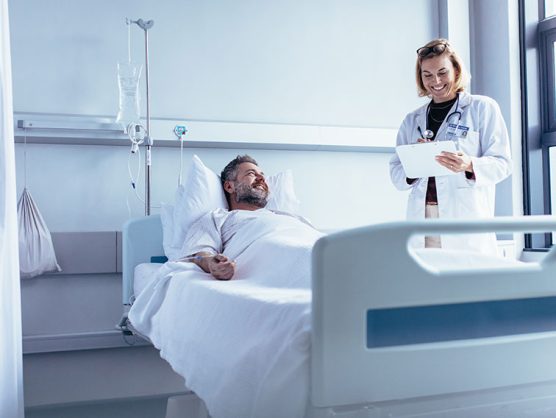 Ärztin und Patient in Krankenzimmer lachen