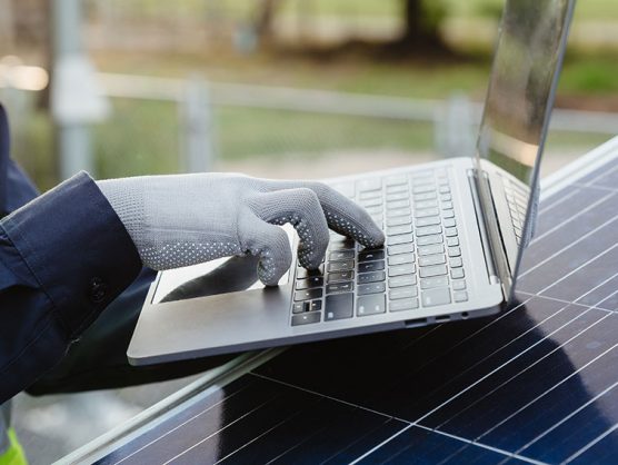 Mann mit Laptop arbeitet an Fotovoltaik-Anlage