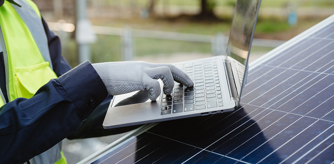 Mann mit Laptop arbeitet an Fotovoltaik-Anlage