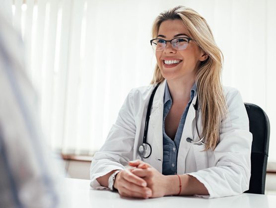 Lächelnde Ärztin sitzt gegenüber von Patientin