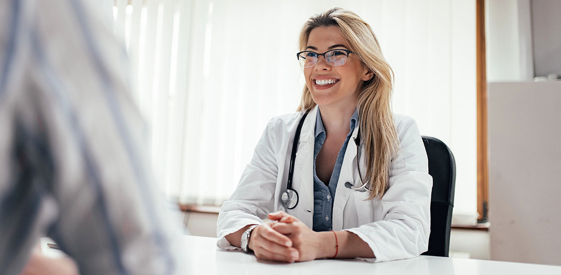 Lächelnde Ärztin sitzt gegenüber von Patientin