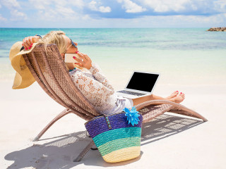 Frau-Laptop-Smartphone-Strand-224679950-FO-Kaspars-Grinvalds