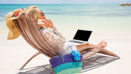 Frau-Laptop-Smartphone-Strand-224679950-FO-Kaspars-Grinvalds