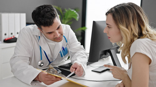 Man and woman doctor and patient having consultation showing medical report at clinic