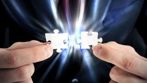 Businessman joins two pieces of the puzzle