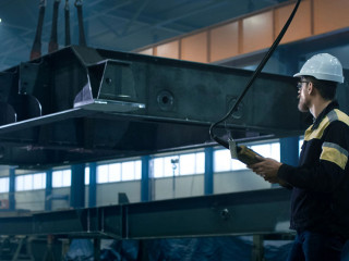 Heavy industry workers are moving a massive metal construction o