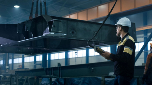 Heavy industry workers are moving a massive metal construction o