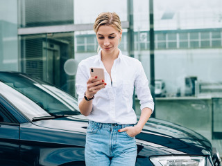 Female driver using smartphone near vehicle