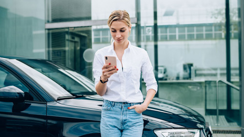 Female driver using smartphone near vehicle