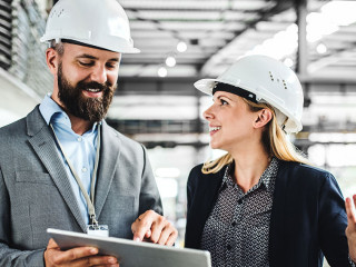 A portrait of an industrial man and woman engineer with tablet in a factory, working.