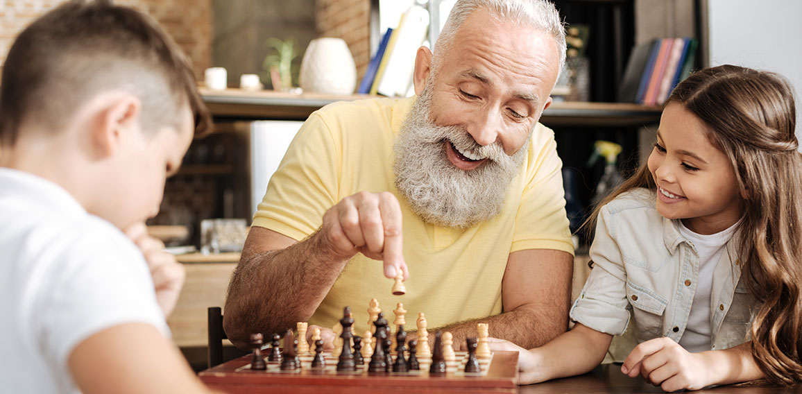 Little girl watching her brother and grandfather play chess