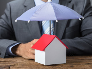 Businessman Protecting House Model With Umbrella