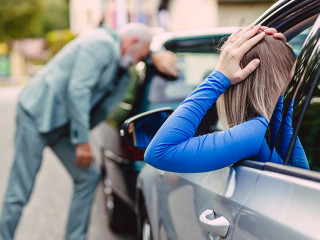 Senior man and young woman arguing after car crash.