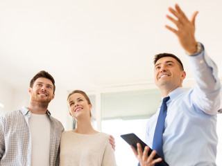 couple and realtor with tablet pc at new home