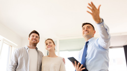 couple and realtor with tablet pc at new home
