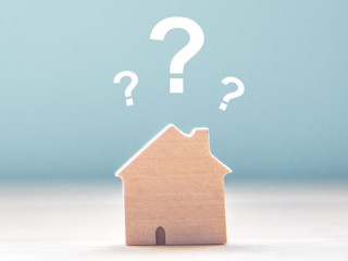 Wood House Model with question marks over the wooden desk and fr