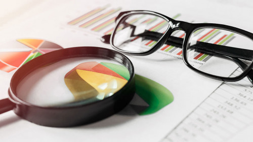 Business reports and a magnifying glass with glasses on table office. Concept of data analysis, investment planning, business analytics.