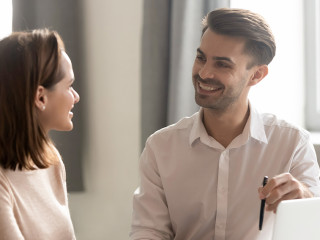 Male and female colleagues talking working together sit at desk