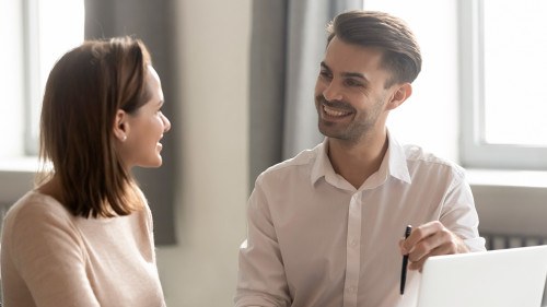 Male and female colleagues talking working together sit at desk