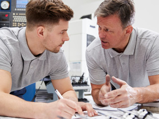 Engineer Showing Apprentice How To Measure CAD Drawings