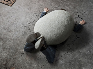 High angle view of businessman crushed by the huge stone on the
