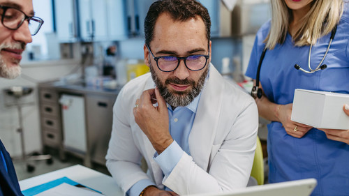 Pharmaceutical sales representative presenting new product to doctors in holding tablet. Presenting new pharmaceutical product, drugs, medication.