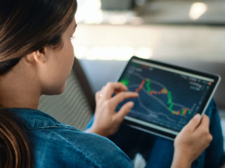Woman Trading Online Using Tablet Computer On Sofa