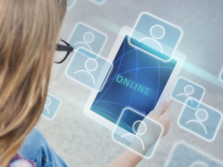 Blonde girl communicating online via tablet on city street. Collage with global community icons on virtual screen