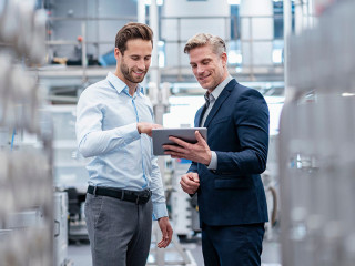 Two businessmen with tablet talking in a modern factory