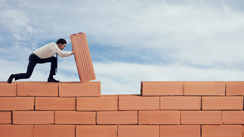 Anzugtraeger-baut-Mauer-262410749-AS-alphaspirit