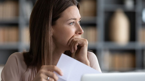 Frau-Papier-Laptop-nachdenklich-328955350-AS-fizkes