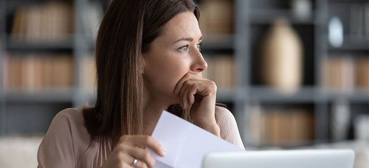 Frau-Papier-Laptop-nachdenklich-328955350-AS-fizkes