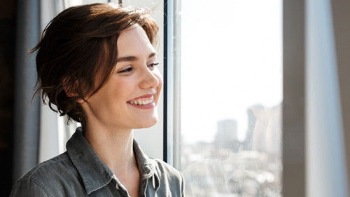 Frau-Laecheln-Fenster-341268547-AS-Drobot-Dean