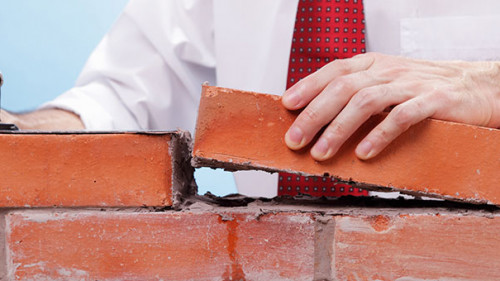 Anzugtraeger-baut-Mauer-236913934-AS-jivimages